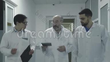 三位男医生在<strong>医院</strong>走廊散步时讨论一位病人`笔记。 4K